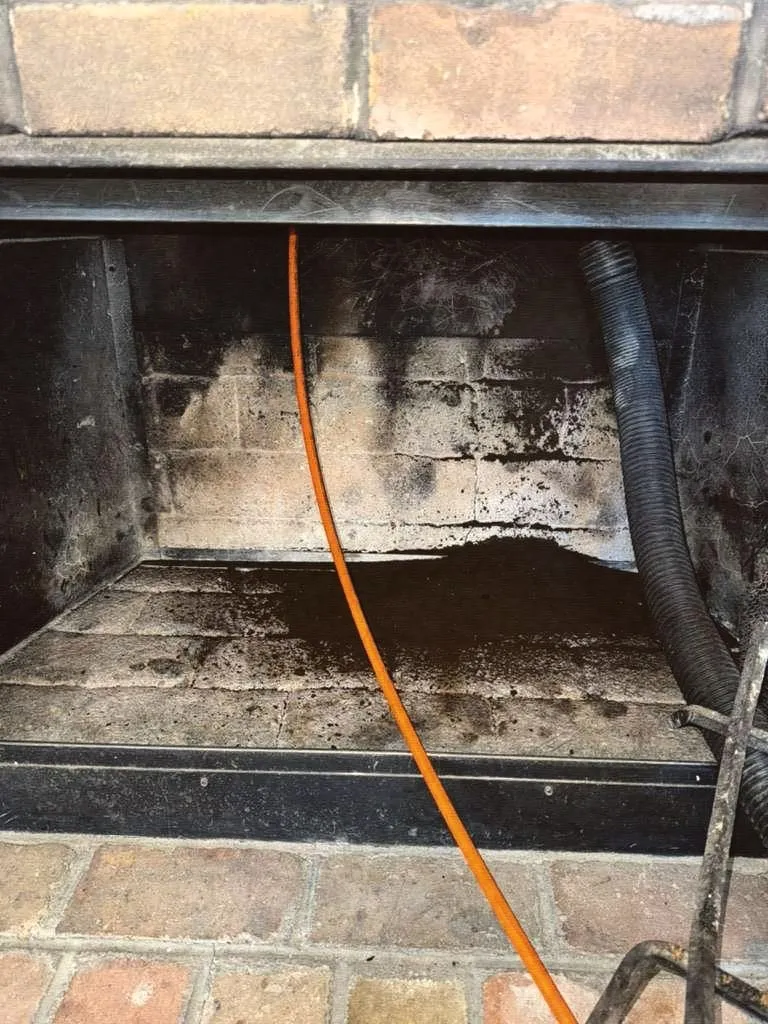 Inside a firebox with a sweeping cable running up into the flue