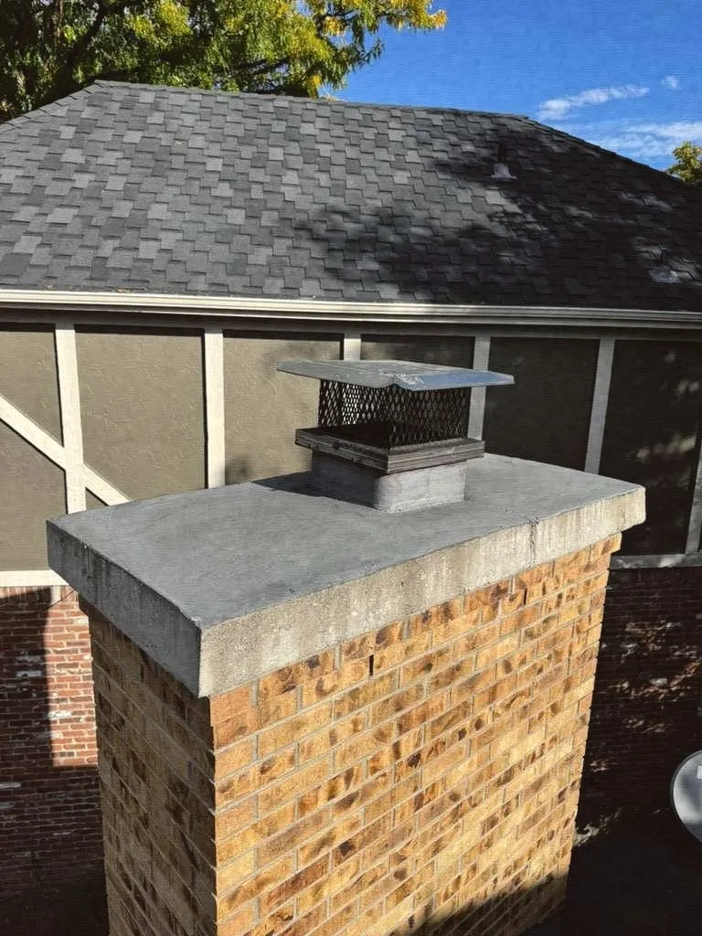 A light brick chimney with a new concrete crown and a steel cap