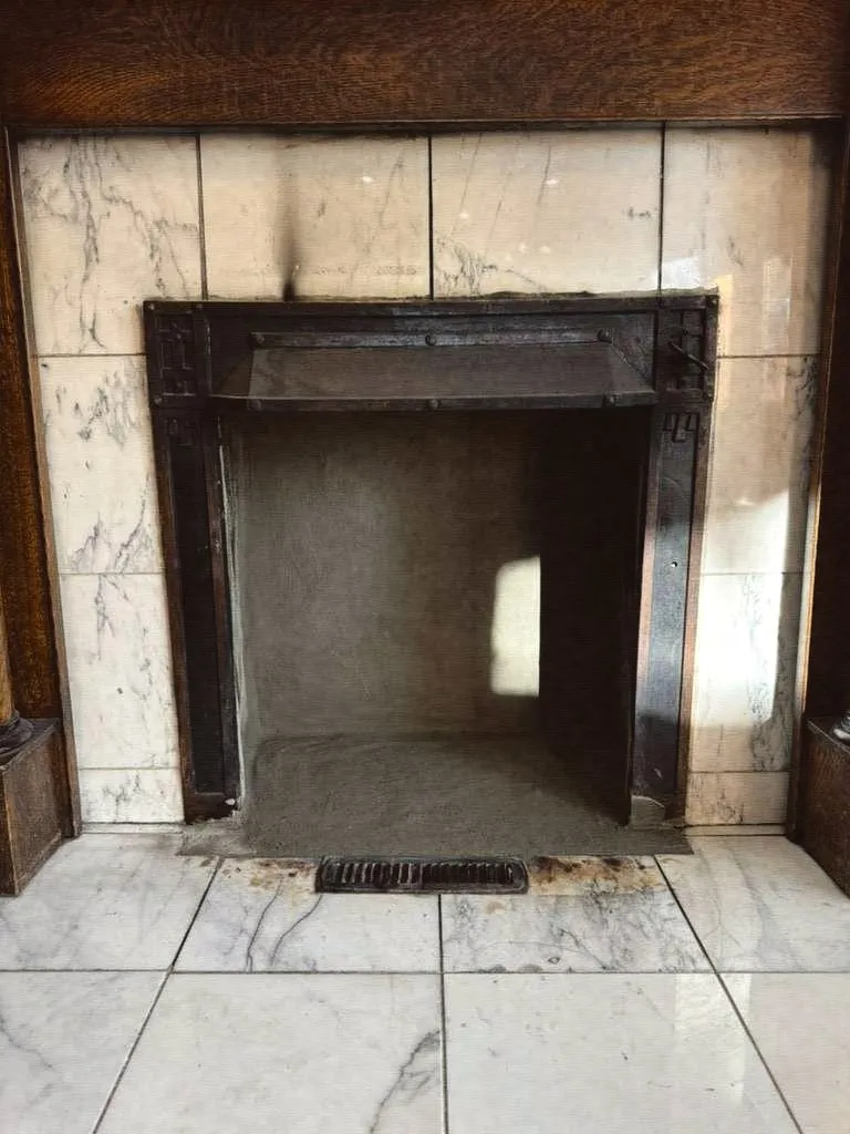 A clean, empty fireplace firebox with a marble surround