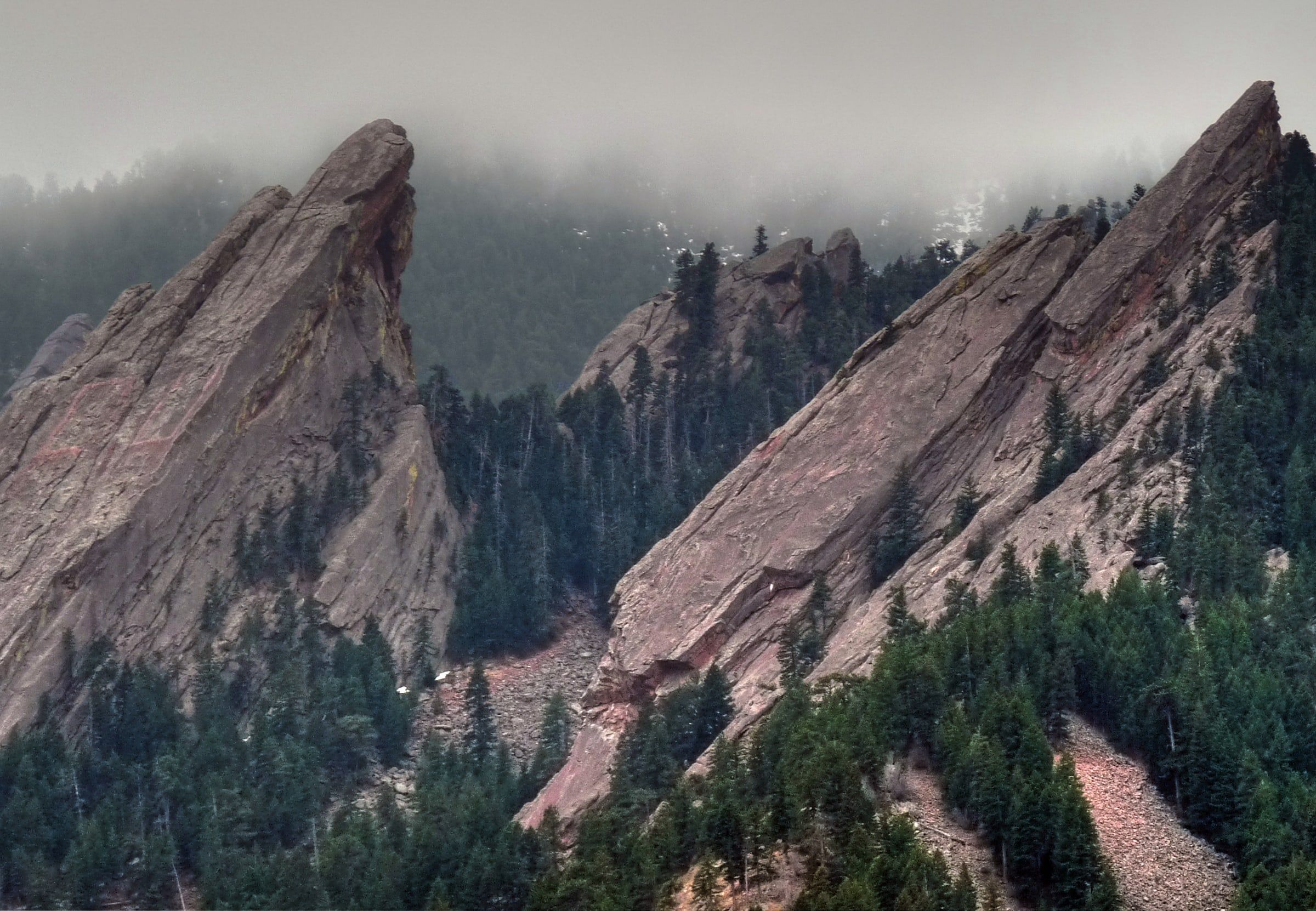 The Flatirons slabs seen from Chautauqua Park, with mist along the rock